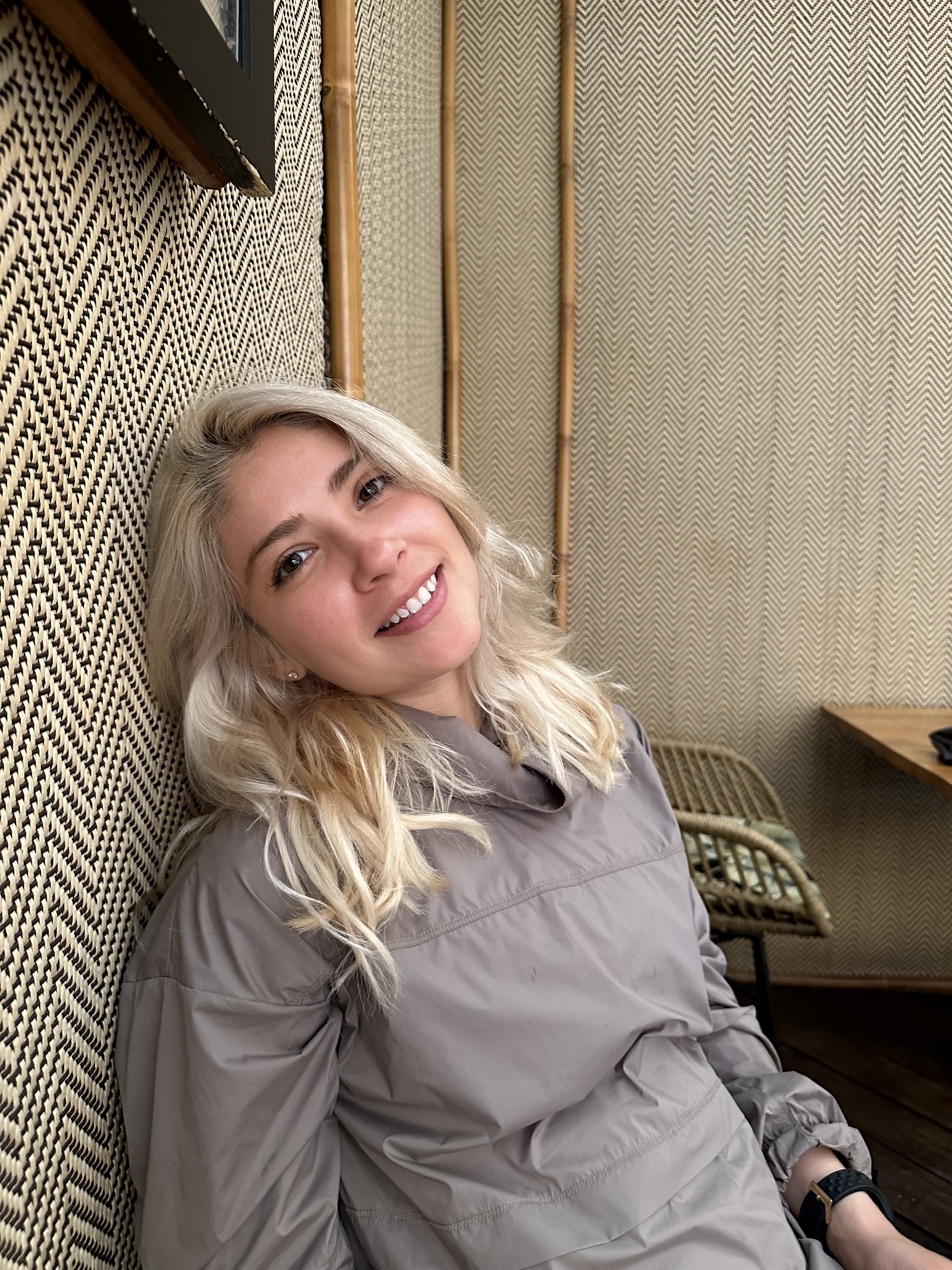 Ana smiling at the camera in a cozy, patterned interior.